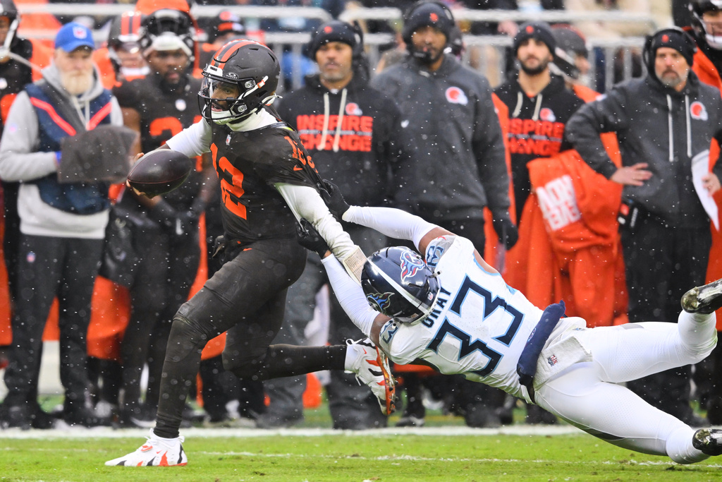 Cleveland Browns quarterback Shedeur Sanders (12) escapes a tackle attempt by Tennessee Titans' Cedric Gray (33) in the first half of an NFL football game in Cleveland, Sunday, Dec. 7, 2025. (AP Photo/David Richard)