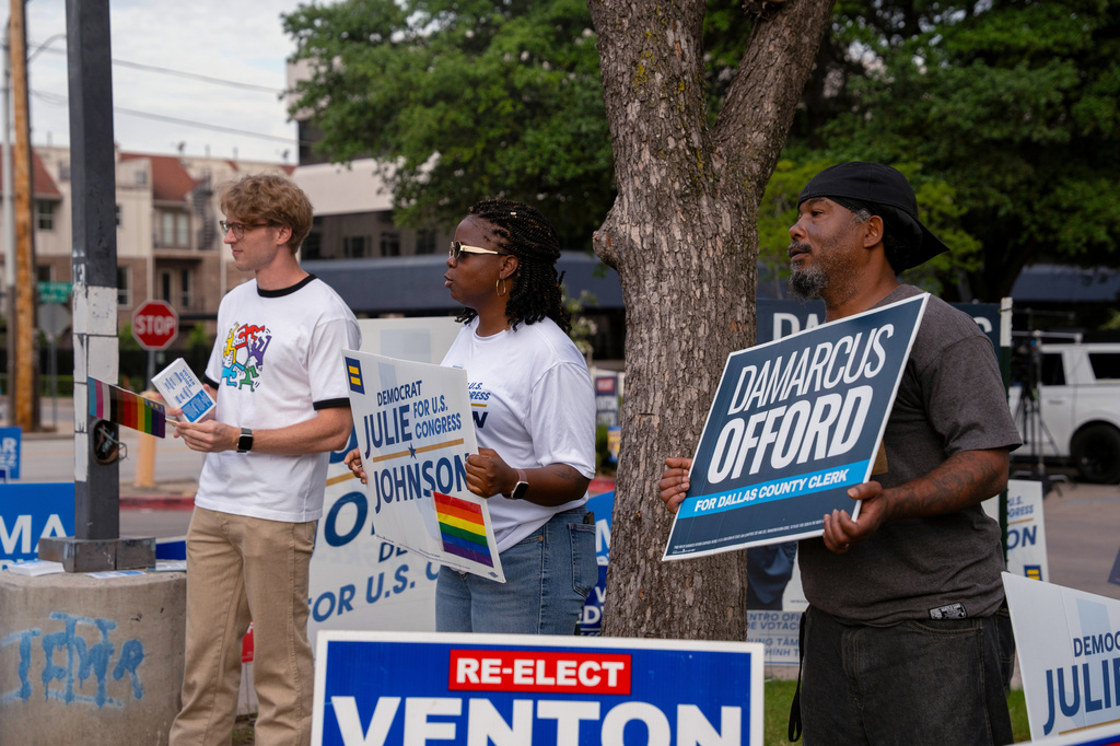 Mike Neal, right, 45, a canvasser for Dallas county clerk candidate Damarcus Offord, Jermaca Brown, center, 32, deputy campaign manager for Rep. Julie Johnson, D-Texas, and Sam Dalton, left, 31, a volunteer with Stonewall Democrats, stand outside the Oak Lawn Branch Library during local and primary runoff elections Tuesday, May 26, 2026, in Dallas. (AP Photo/Gabriela Passos)