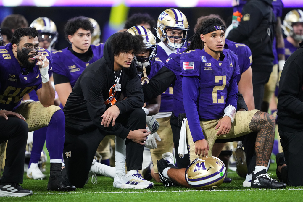 Washington players, including quarterback Demond Williams Jr. (2) kneel as they wait for teammate Raiden Vines-Bright to be taken off of the field in a stretcher after an injury during a play against Purdue during the first half of an NCAA college football game, Saturday, Nov. 15, 2025, in Seattle. (AP Photo/Lindsey Wasson)