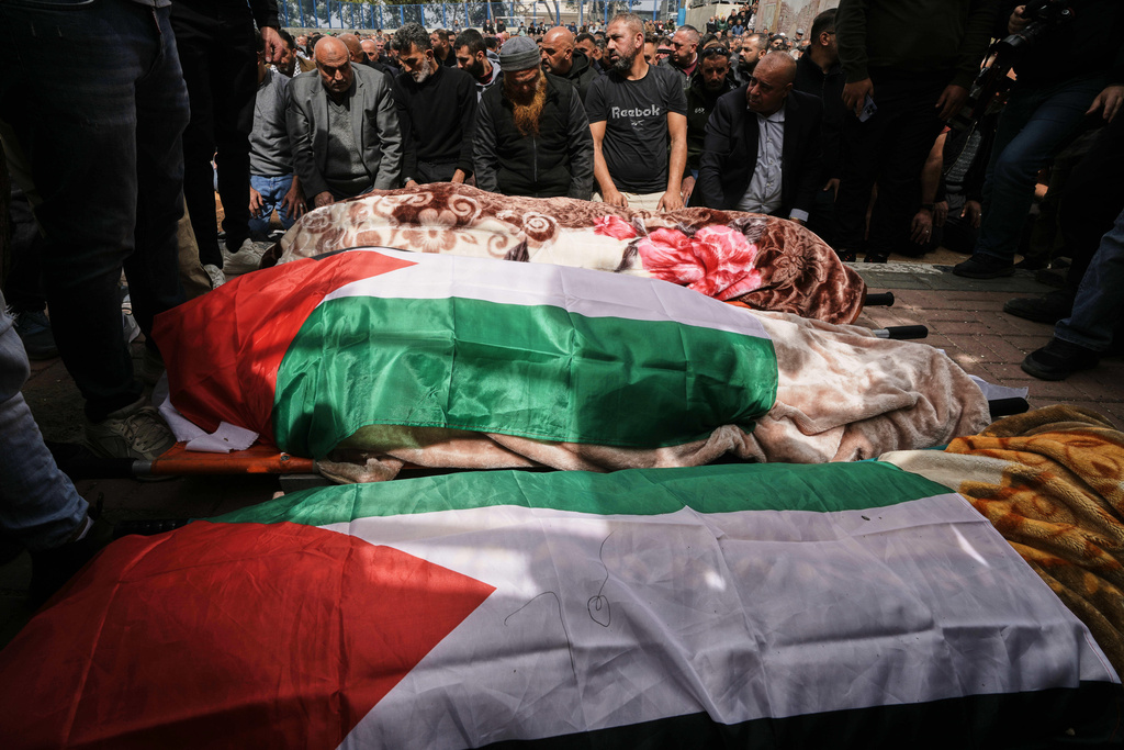 Palestinian men pray during the funeral of three Palestinian women who were killed in an Iranian strike in the West Bank village of Beit Awa, near Hebron, Thursday, March 19, 2026. (AP Photo/Mahmoud Illean)