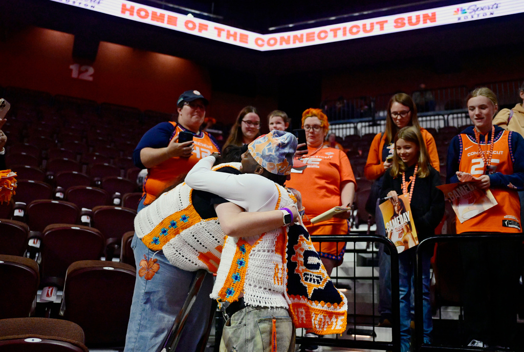 Connecticut Sun's Saniya Rivers, front right, embraces fan Adrianna Wilkinson, front left, of Brockton, Mass., before her team's last WNBA basketball game, against the Toronto Tempo, Thursday, Sept. 24, 2026, at Mohegan Sun in Uncasville, Conn. Wilkinson crotched the vest Rivers is wearing. (AP Photo/Jessica Hill)