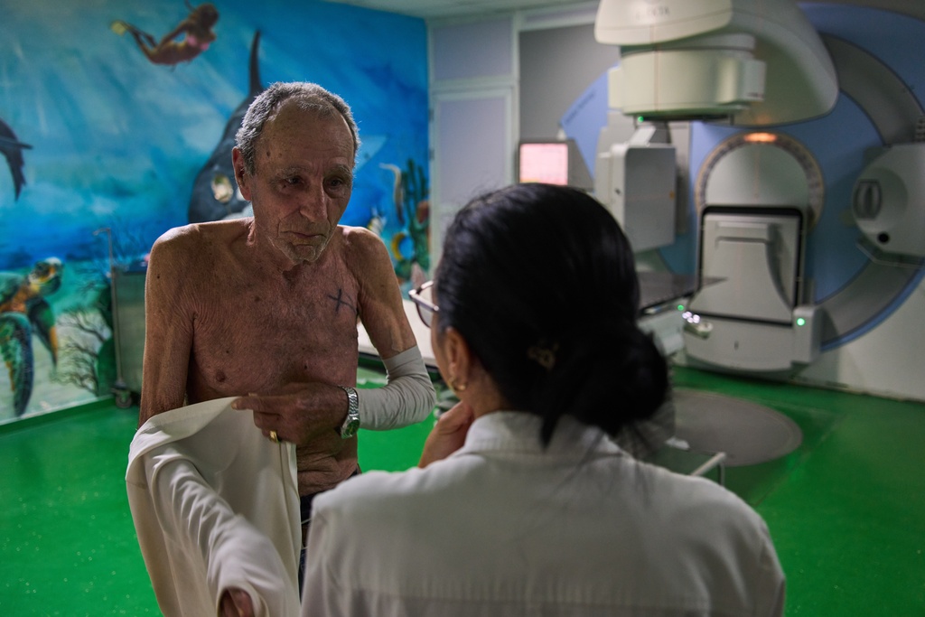 Jorge Elias speaks with the doctor after his radiotherapy session at the National Institute of Oncology and Radiology in Havana, Cuba, Friday, Feb. 20, 2026. (AP Photo/Ramon Espinosa)