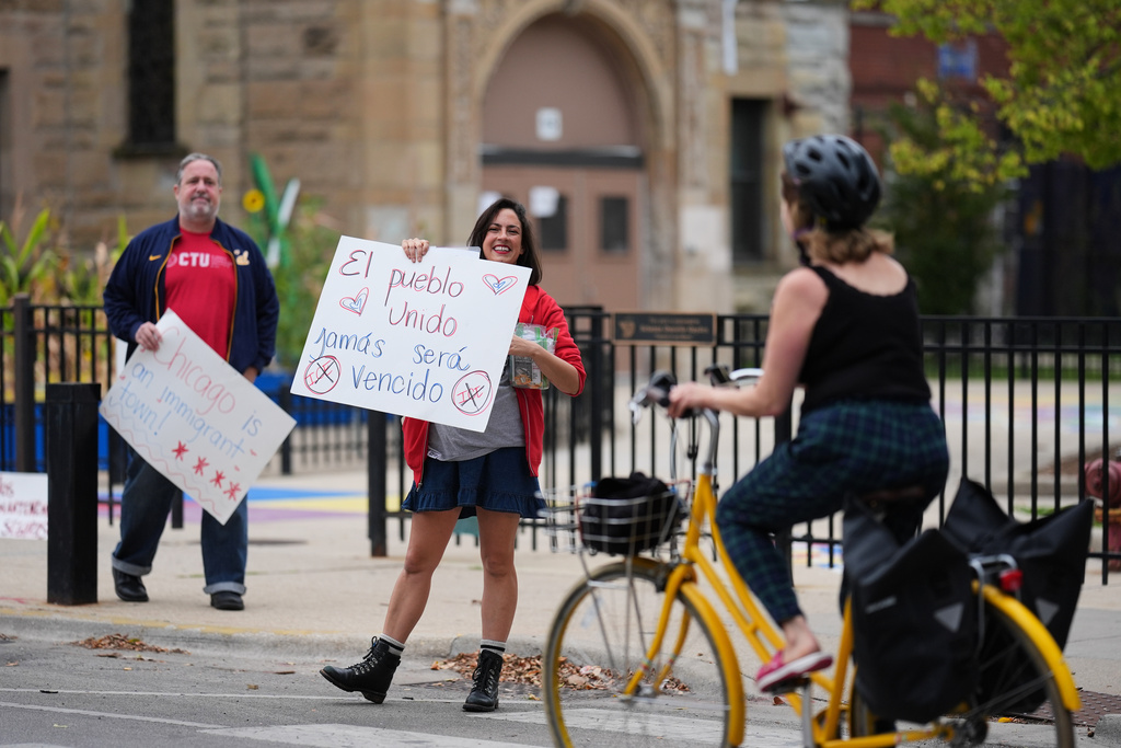First grade teacher Maria Heavener holds a sign that reads in Spanish, "The people, united, will never be defeated," as she participates in Sidewalk Solidarity, a weekly show of support by Chicago Teachers Union members for the school's immigrant community in Chicago's Logan Square neighborhood, Friday, Oct. 17, 2025. (AP Photo/Rebecca Blackwell)