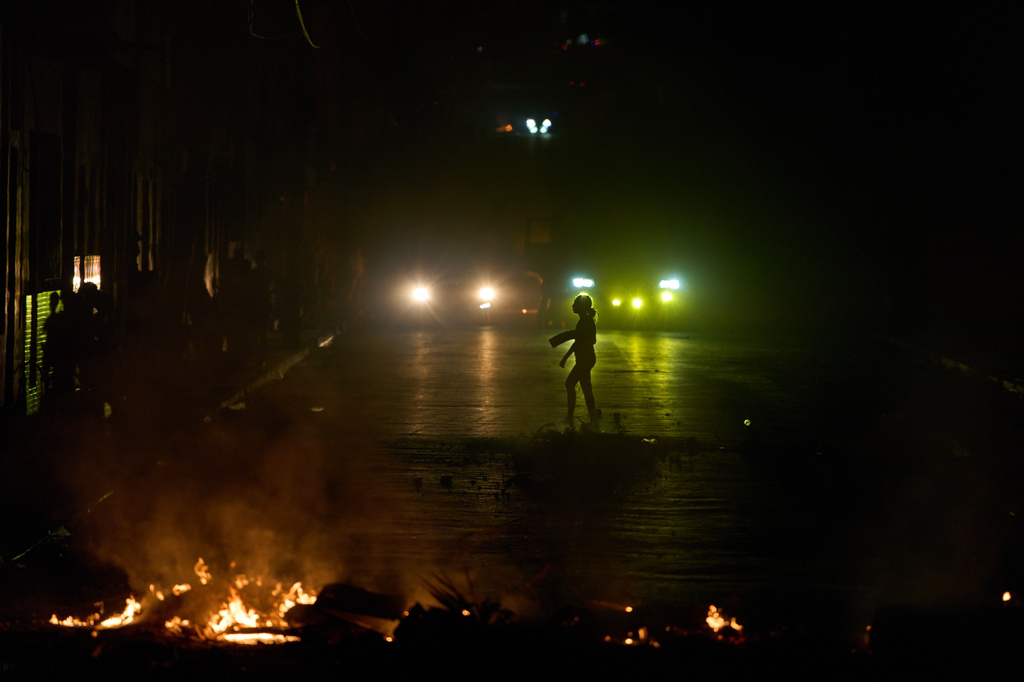 A woman walks in front of a barricade set up by residents protesting against prolonged power outages in Havana, Cuba, Wednesday, May 13, 2026. (AP Photo/Ramon Espinosa)