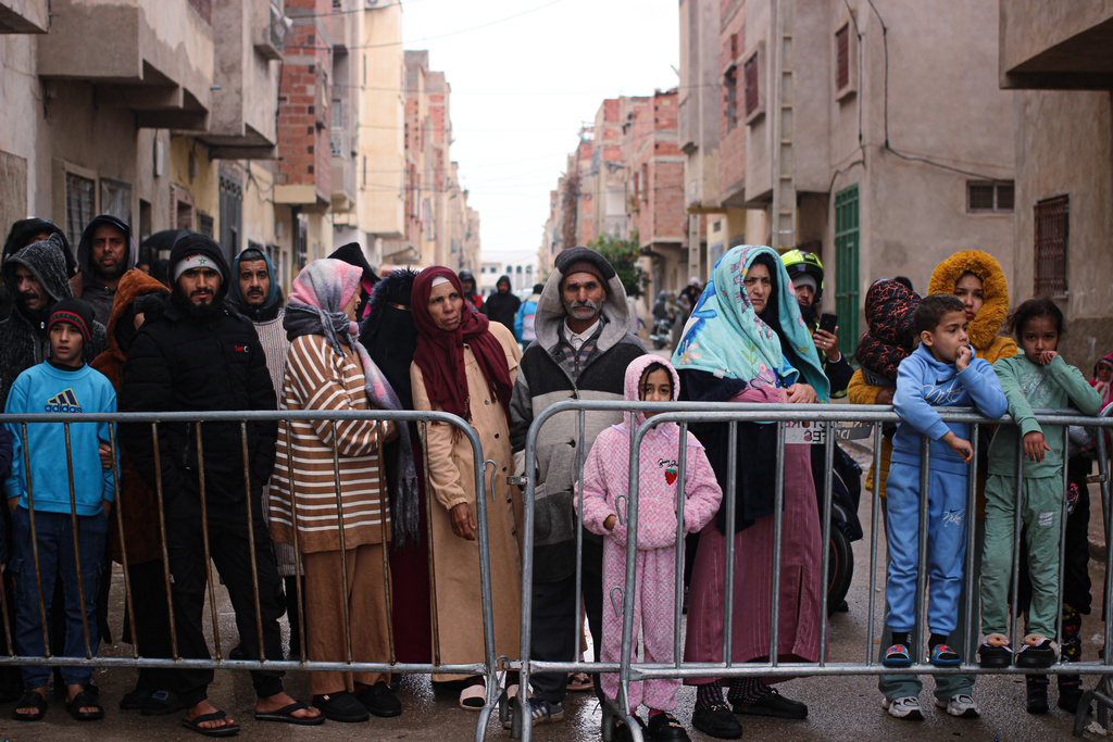 Residents watch as rescue workers search for survivors, amid the wreckage of two collapsed buildings, in Fez, Morocco, Wednesday, Dec. 10, 2025. (AP Photo/Hanane Boukili)