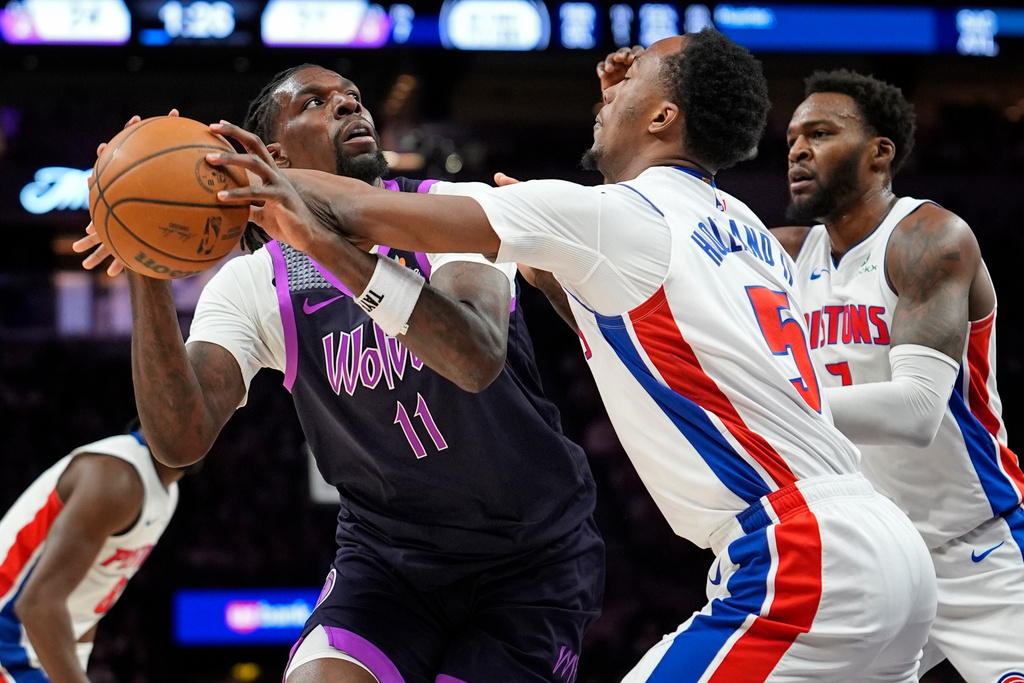 Detroit Pistons forward Ron Holland (5) knocks the ball away from Minnesota Timberwolves center Naz Reid (11) as Pistons forward Paul Reed, right, approaches in the first quarter of an NBA basketball game Saturday, March 28, 2026, in Minneapolis. (AP Photo/Bruce Kluckhohn)