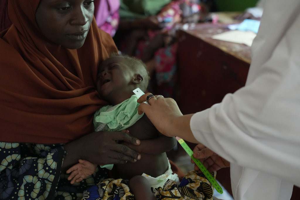 Halimah Muhammad, a local health worker, right, attends to a child suffering from malnutrition, as his mother Larai Malami, a 35-year-old mother of 10, holds him at the Rumbukawa Primary Health Centre in Sokoto, northwestern Nigeria, Thursday, July 16, 2026. (AP Photo/Sunday Alamba)