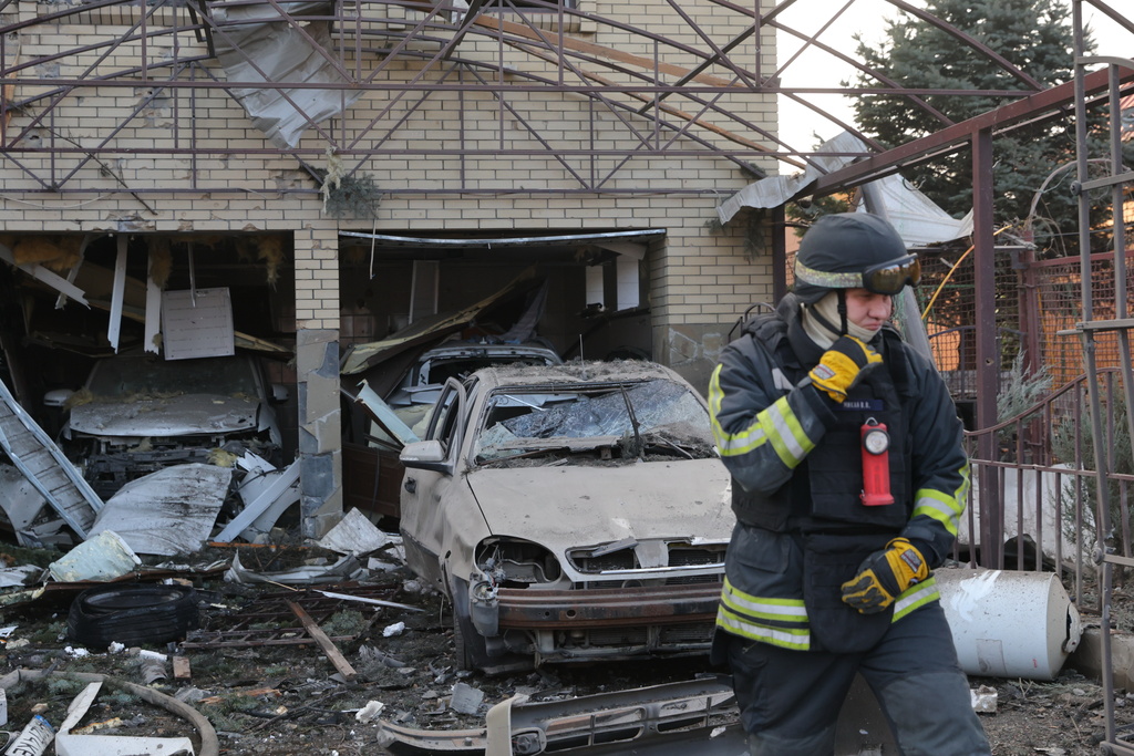 A rescue worker walks in front of a residential house damaged after a Russian attack on Zaporizhzhia, Ukraine, Friday, Dec. 19, 2025. (AP Photo/Kateryna Klochko)