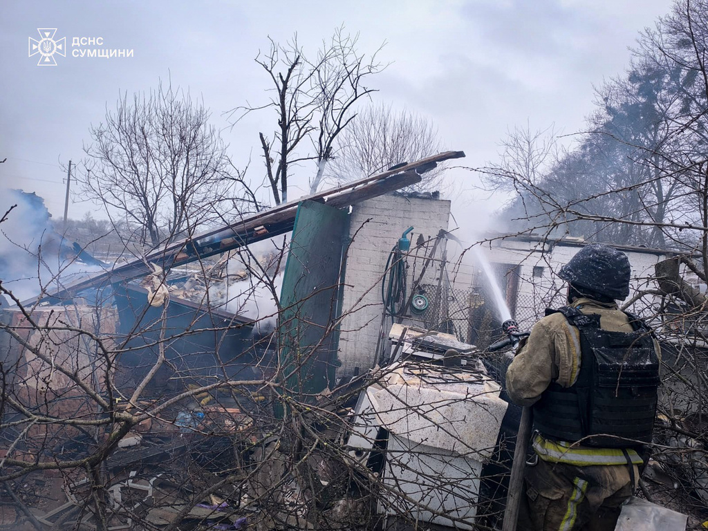 In this photo provided by the Ukrainian Emergency Service, a firefighter puts out the fire in private houses following a Russian air attack in Sumy region, Ukraine, Tuesday, Feb. 17, 2026. (Ukrainian Emergency Service via AP)
