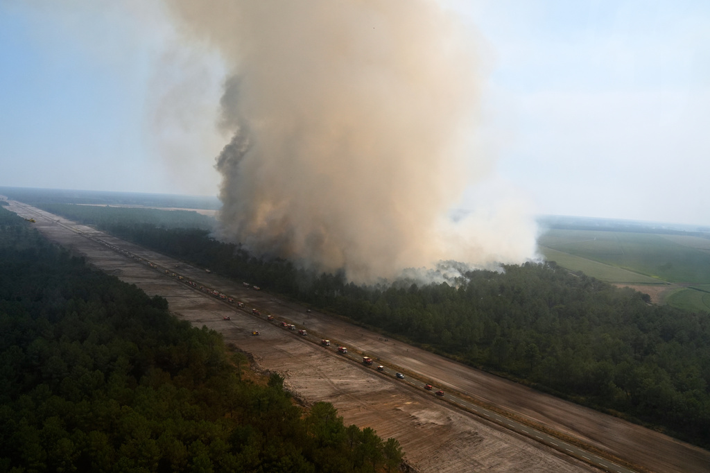 Firefighting vehicles line a road to suppress fires near Ares, during wildfires in the area of southwestern France, Tuesday, July 28, 2026. (AP Photo/Baz Ratner, Pool)