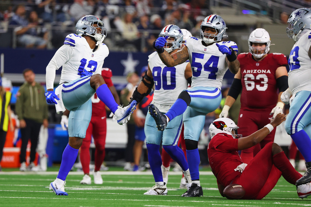 Dallas Cowboys' Dante Fowler Jr. (13) and Sam Williams (54) celebrate after sacking Arizona Cardinals' Jacoby Brissett, bottom right, in the second half of an NFL football game Monday, Nov. 3, 2025, in Arlington, Texas. (AP Photo/Richard Rodriguez)