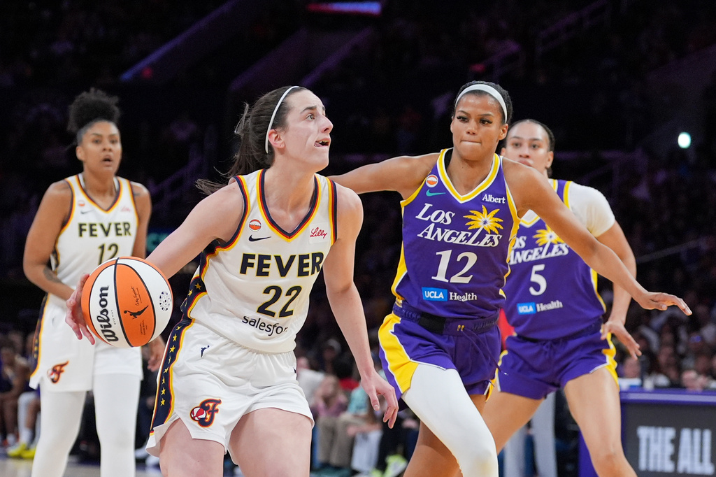 Indiana Fever guard Caitlin Clark (22) drives past Los Angeles Sparks guard-forward Rae Burrell (12) during the first half of a WNBA basketball game Wednesday, May 13, 2026, in Los Angeles. (AP Photo/Jae C. Hong)