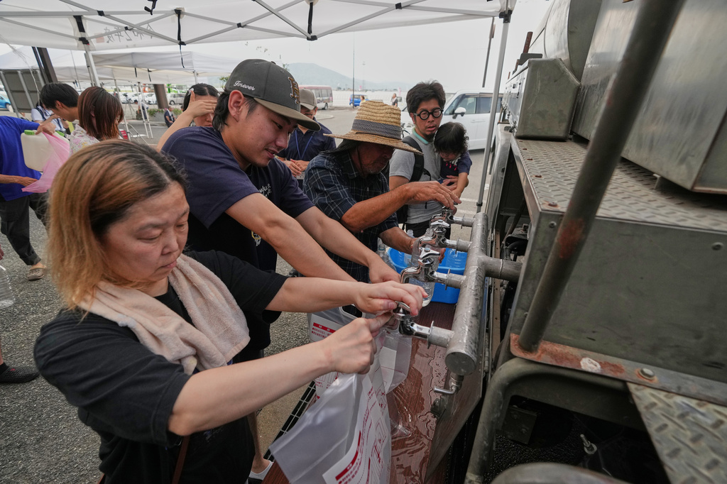 Residents receive a water supply after water service was disrupted following an earthquake in Hikawa, Kumamoto Prefecture, southern Japan, Thursday, July 30, 2026. (AP Photo/Hiro Komae)