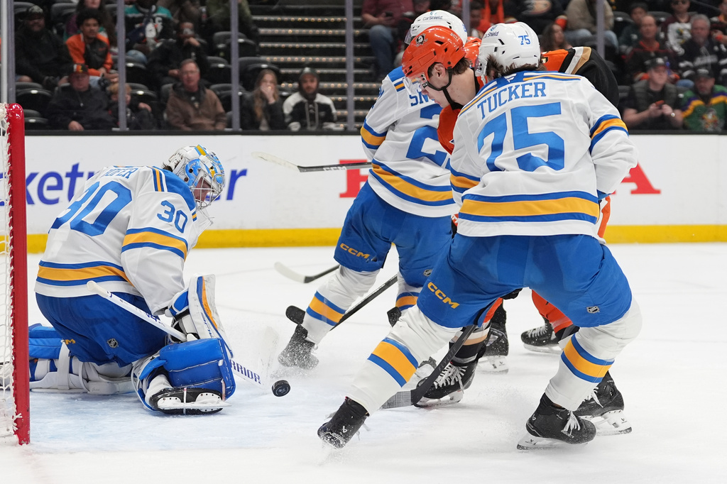 St. Louis Blues goaltender Joel Hofer (30) blocks a shot from Anaheim Ducks right wing Beckett Sennecke, center, as St. Louis Blues defenseman Tyler Tucker (75) defends during the third period of an NHL hockey game Friday, April 3, 2026, in Anaheim, Calif. (AP Photo/Gregory Bull)