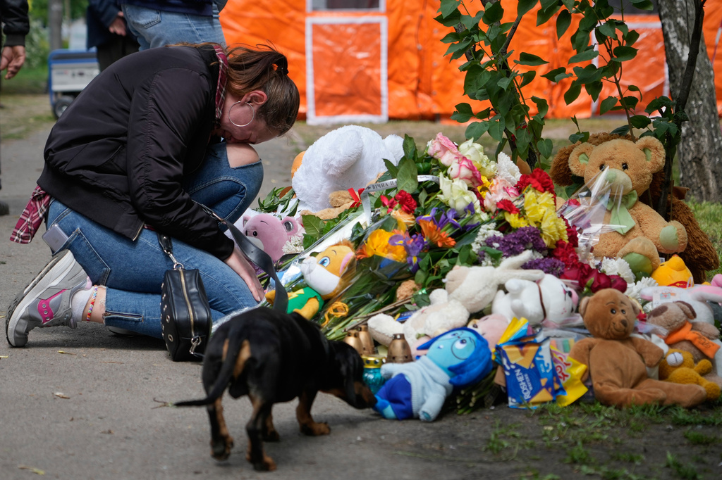 A women cries as she lays down flowers in front of a house heavily damaged after a Russian strike on residential neighbourhood in Kyiv, Ukraine, Friday, May 15, 2026. (AP Photo/Efrem Lukatsky)