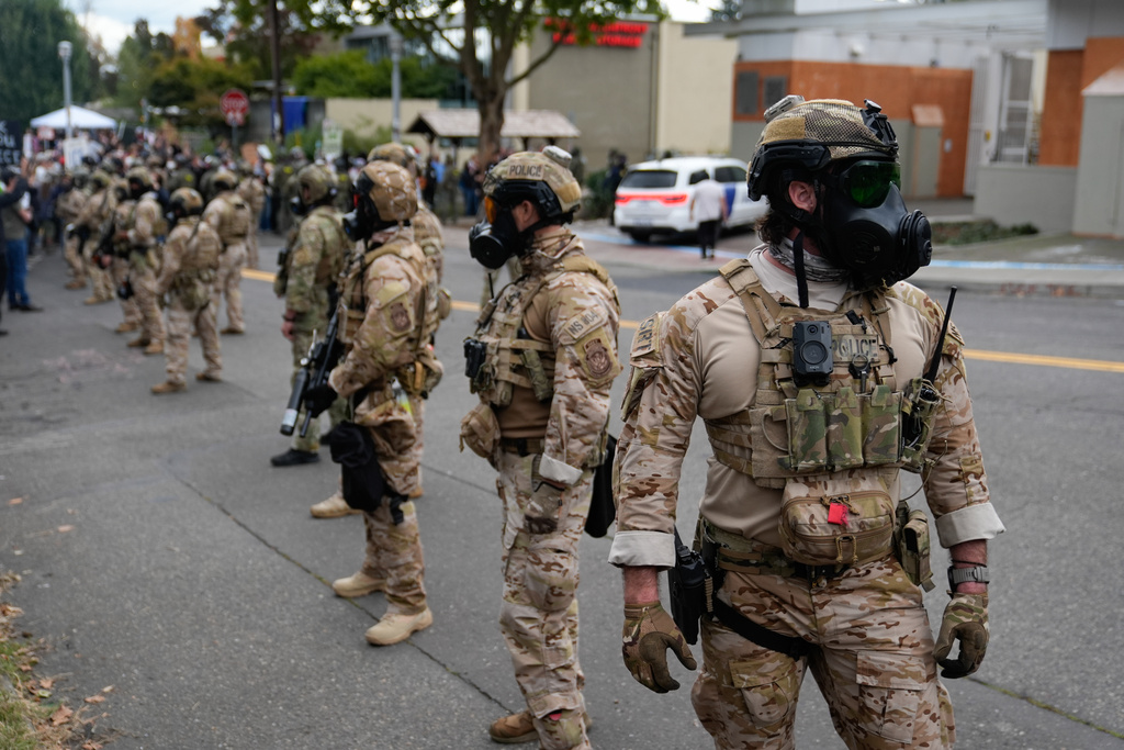 Law enforcement officers block the road for a vehicle to enter a U.S. Immigration and Customs Enforcement facility on Saturday, Oct. 4, 2025, in Portland, Ore. (AP Photo/Jenny Kane)