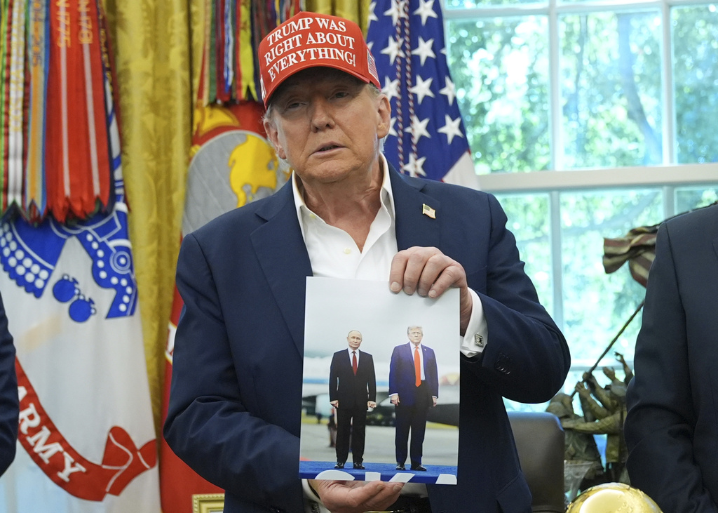 President Donald Trump holds a photo of himself with Russian President Vladimir Putin during an announcement in the Oval Office of the White House, Friday, Aug. 22, 2025, in Washington. (AP Photo/Jacquelyn Martin)
