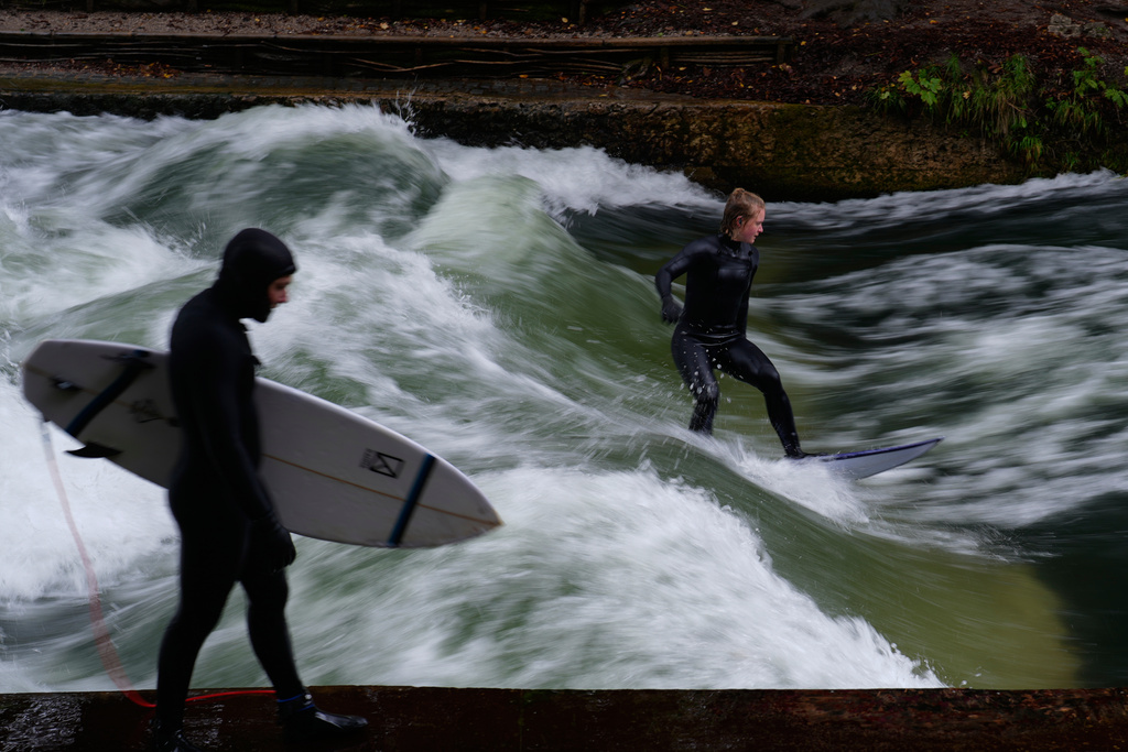 FILE - Surfer ride on an artificial wave in the river 'Eisbach' at the 'Englischer Garten' (English Garden) downtown in Munich, Germany, Monday, Oct. 6, 2025. (AP Photo/Matthias Schrader, File)