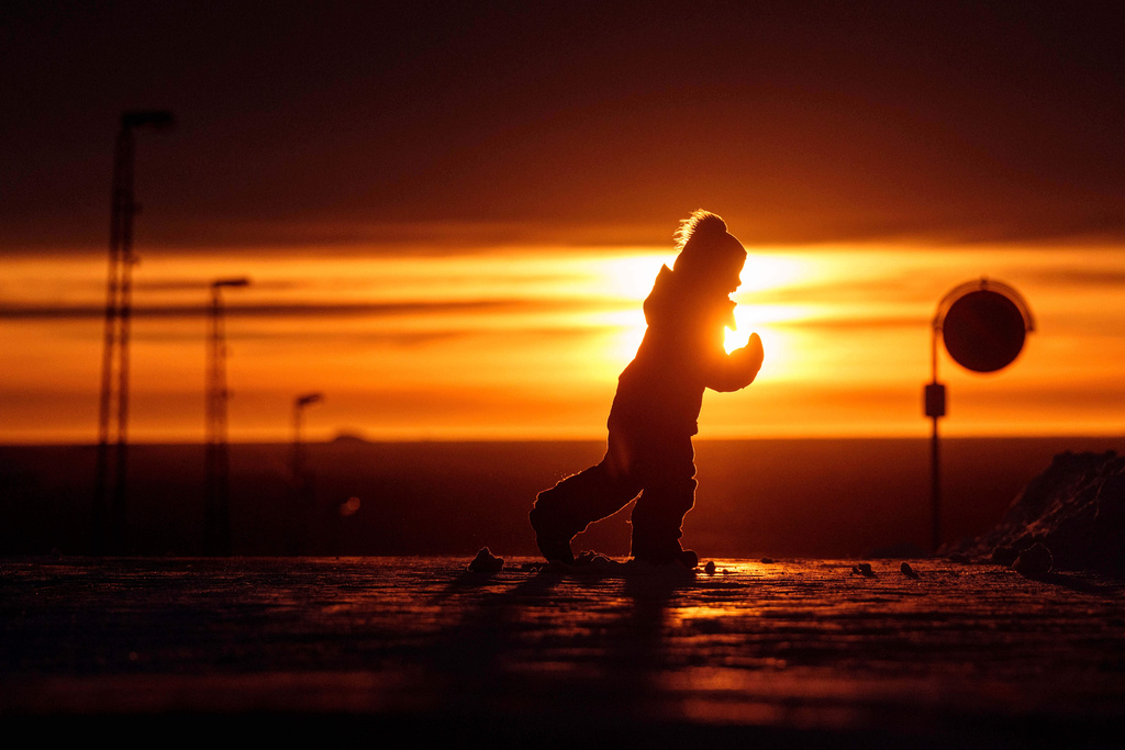 A boy runs across a street at a sunset in Nuuk, Greenland, on Wednesday, Jan. 21, 2026. (AP Photo/Evgeniy Maloletka)