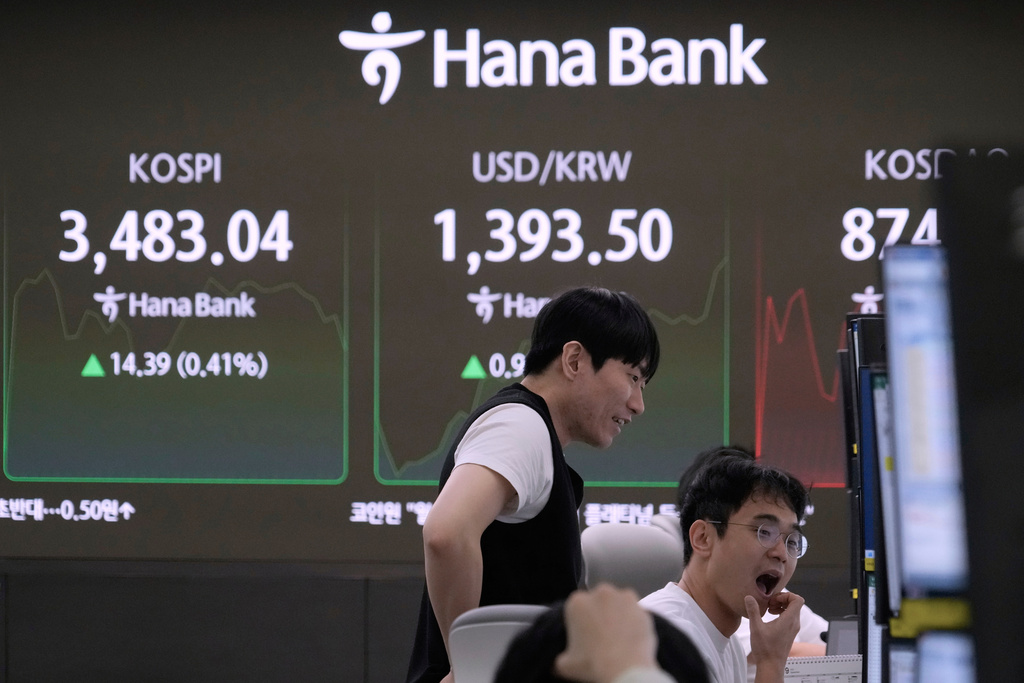 Currency traders watch monitors near a screen showing the Korea Composite Stock Price Index (KOSPI), top left, and the foreign exchange rate between U.S. dollar and South Korean won at the foreign exchange dealing room of the Hana Bank headquarters in Seoul, South Korea, Tuesday, Sept. 23, 2025. (AP Photo/Ahn Young-joon)