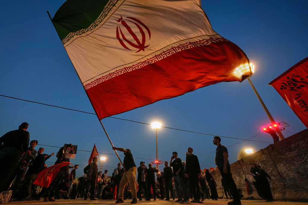 A man waves an Iranian flag during funeral ceremonies for slain Iranian Supreme Leader Ayatollah Ali Khamenei and members of his family at Imam Khomeini Mosalla Grand Mosque in Tehran, Iran, Sunday, July 5, 2026. (AP Photo/Altaf Qadri)