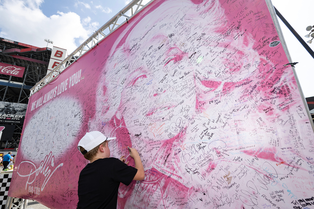 Henry Bailey, 7, from Kentucky signs his name to a tribute sign to the late Dolly Parton before a NASCAR Cup Series auto race Saturday, Sept. 19, 2026, in Bristol, Tenn. (AP Photo/Wade Payne)
