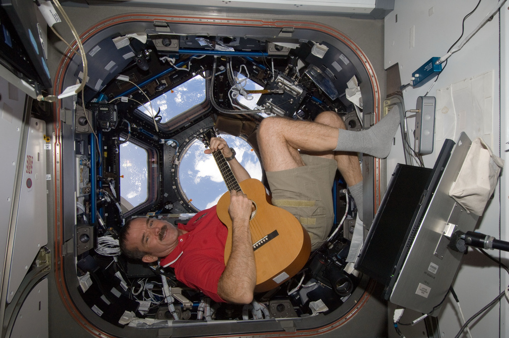 In this photo provided by NASA, Canadian astronaut Chris Hadfield plays guitar in the cupola module of the International Space Station on Dec. 25, 2012. (NASA via AP)