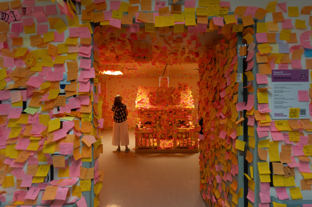 A visitor stands in the Gratitude Room, which is covered with handwritten notes, during the "Hospital of Emotions" exhibition inside a former hospital building in Los Angeles, Wednesday, July 22, 2026.(AP Photo/Jae C. Hong)