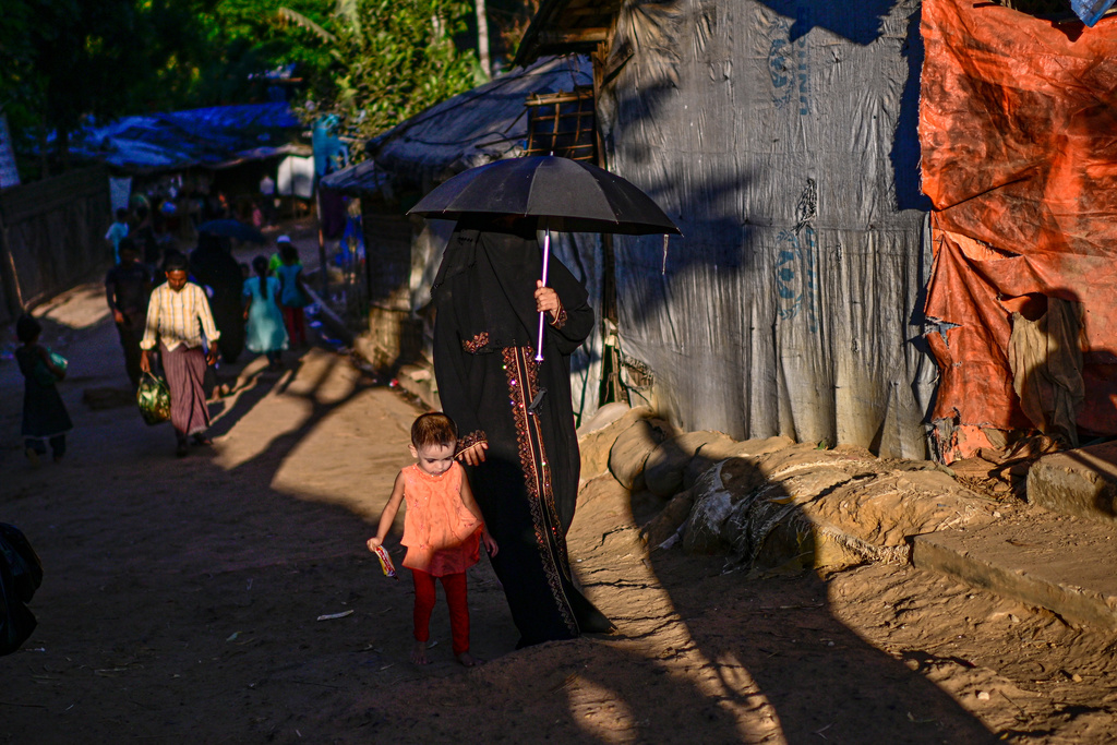 A Rohingya refugee woman walks with her child inside the Rohingya refugee camp, home to over a million of Myanmar's persecuted Rohingya minority, in Cox's Bazar, Bangladesh, Friday, Nov. 21, 2025. (AP Photo/Mahmud Hossain Opu)
