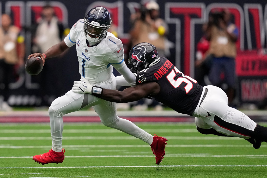 Tennessee Titans quarterback Cam Ward (1) is pressured by Houston Texans defensive end Will Anderson Jr. (51) during the first half of an NFL football game Sunday, Sept. 28, 2025, in Houston. (AP Photo/David J. Phillip)