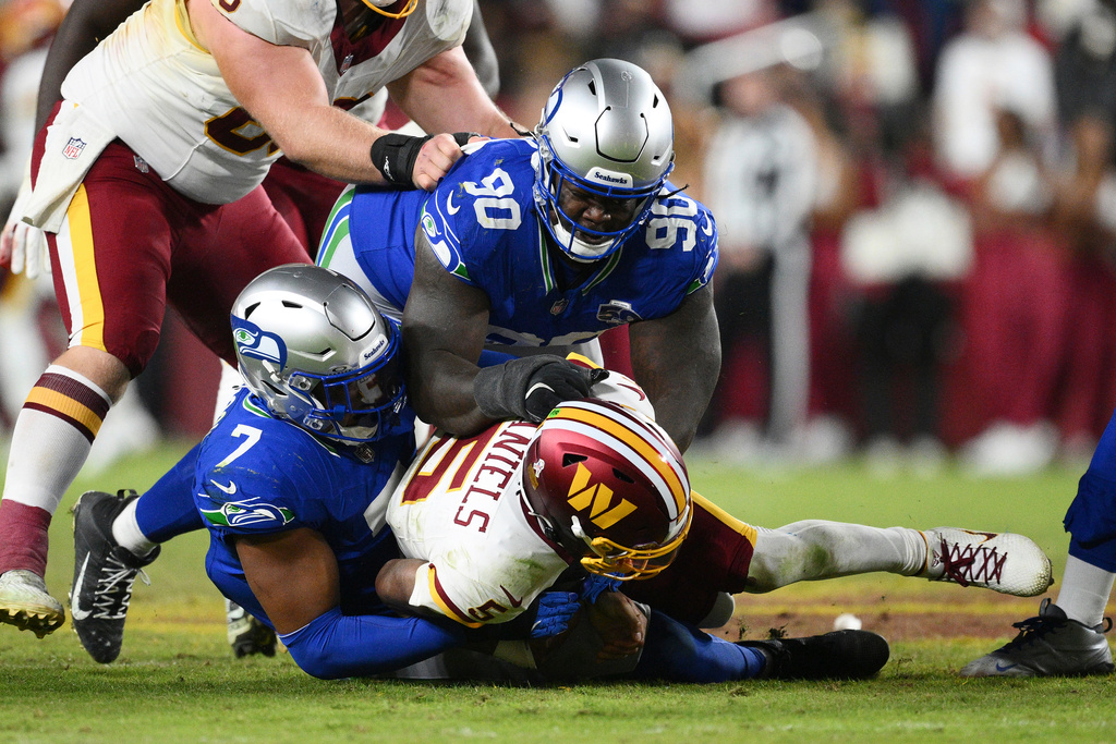 Washington Commanders quarterback Jayden Daniels (5) is sacked by Seattle Seahawks linebacker Uchenna Nwosu (7) and defensive tackle Jarran Reed (90) during the second half of an NFL football game, Sunday, Nov. 2, 2025, in Landover, Md. (AP Photo/Nick Wass)