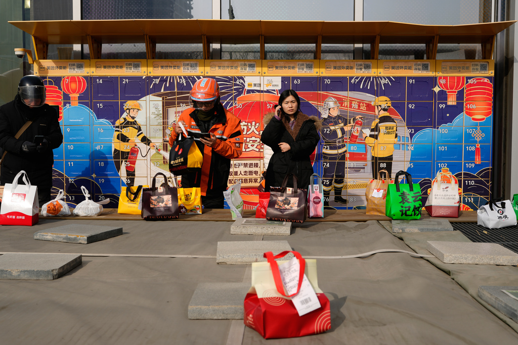 A woman makes a call near an area for delivery drivers to leave their parcels outside a mall in Beijing, China, Thursday, Jan. 15, 2026. (AP Photo/Ng Han Guan)