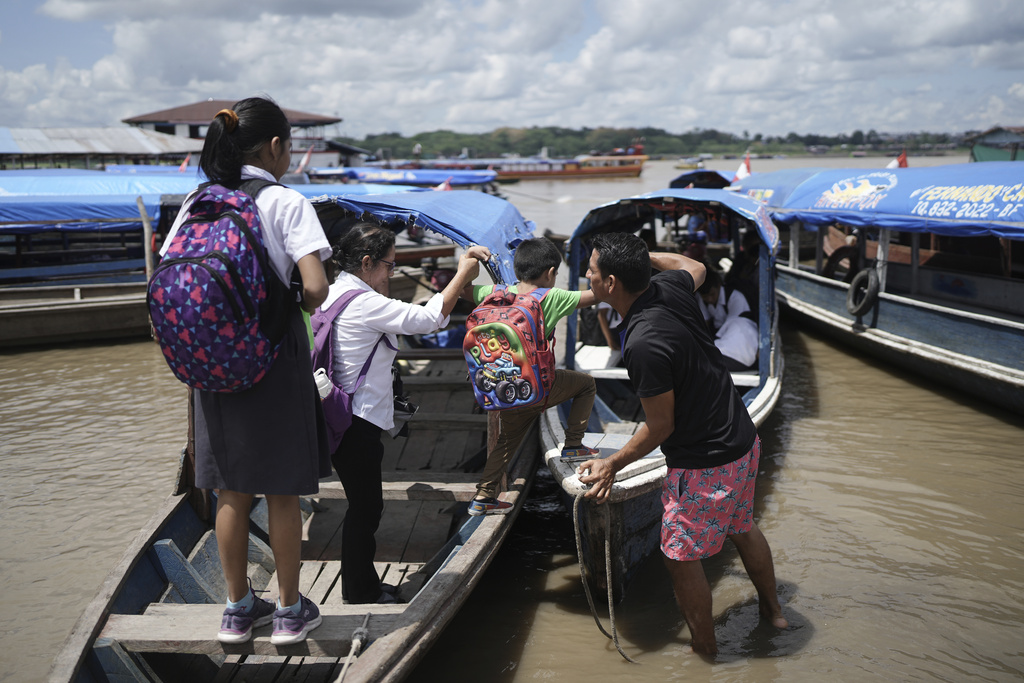 Salvador Mitidieri helps schoolchildren board his boat after classes in Santa Rosa, Peru, Monday, Aug. 18, 2025. (AP Photo/Ivan Valencia)