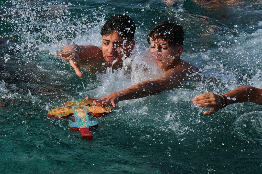 Youth pilgrims try to catch the cross thrown by an Orthodox priest into the water during an Epiphany ceremony to bless the sea in the southeastern village of Xylophagou, Cyprus, Tuesday, Jan. 6, 2026. (AP Photo/Petros Karadjias)