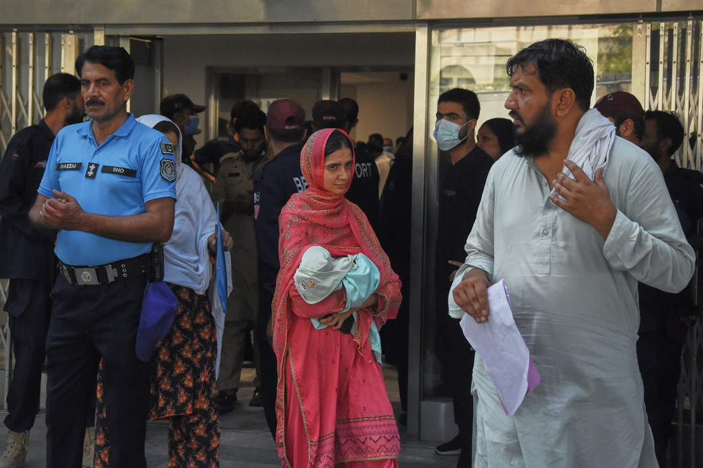 A woman carries her newborn baby out from a nursery in the gynecology ward of a hospital following a fire in Islamabad, Pakistan, Wednesday, Aug. 26, 2026. (AP Photo)