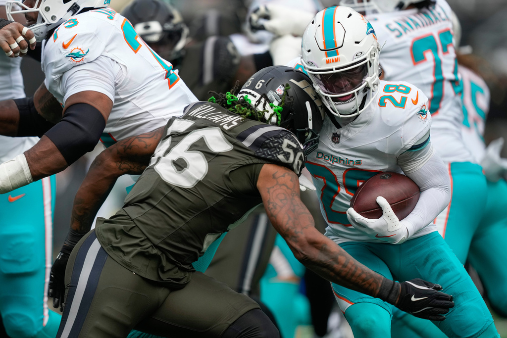 New York Jets linebacker Quincy Williams (56) hits Miami Dolphins running back De'Von Achane (28) during the second quarter of an NFL football game, Sunday, Dec. 7, 2025, in East Rutherford, N.J. (AP Photo/Yuki Iwamura)