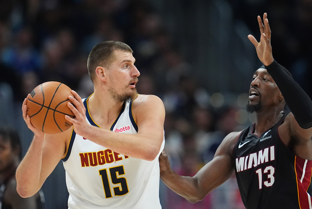 Denver Nuggets center Nikola Jokic, left, looks to pass the ball as Miami Heat center Bam Adebayo defends in the first half of an NBA basketball game Wednesday, Nov. 5, 2025, in Denver. (AP Photo/David Zalubowski)