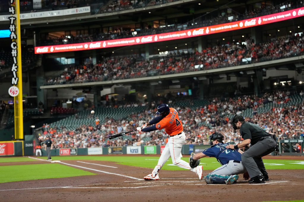 Houston Astros' Yordan Alvarez (44) hits a home run as Seattle Mariners catcher Cal Raleigh reaches for the pitch during the first inning of a baseball game Friday, Aug. 14, 2026, in Houston. (AP Photo/David J. Phillip)