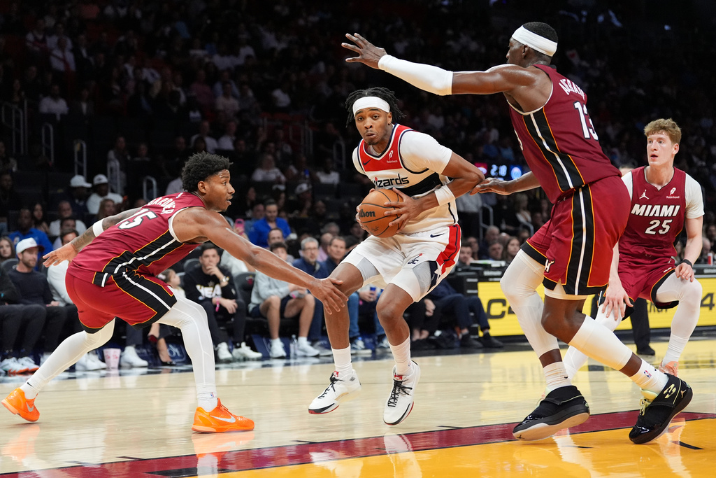 Washington Wizards guard Bilal Coulibaly, center, comes under pressure from Miami Heat forward Myron Gardner (15), center Bam Adebayo (13), and guard Kasparas Jakucionis (25) during the first half of an NBA basketball game, Tuesday, March 10, 2026, in Miami. (AP Photo/Rebecca Blackwell)