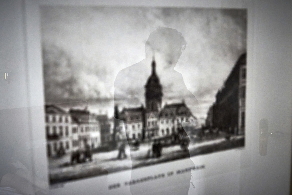 Former Xinjiang government engineer Nureli Abliz, a Uyghur Muslim, is reflected in a historical image of Mannheim's central square, as he prays in a hotel room during an interview in Mannheim, Germany, where he now lives in exile, Wednesday, July 23, 2025. (AP Photo/David Goldman)