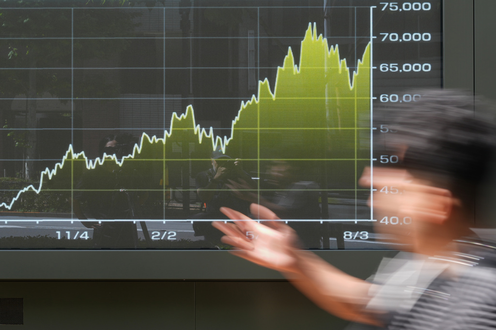A person walk in front of an electronic stock chart board showing Japan's Nikkei index at a securities firm Tuesday, Aug. 18, 2026, in Tokyo. (AP Photo/Eugene Hoshiko)
