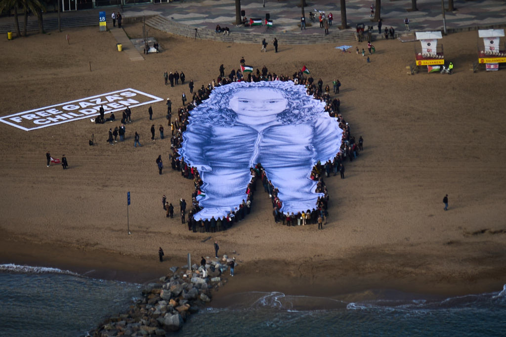 FILE.- People hold a giant portrait of Hind Rajab, a five-year-old Palestinian girl who was killed during the war in Gaza, on a beach in Barcelona, Spain, Thursday, Jan. 29, 2026. (AP Photo/Emilio Morenatti, File)