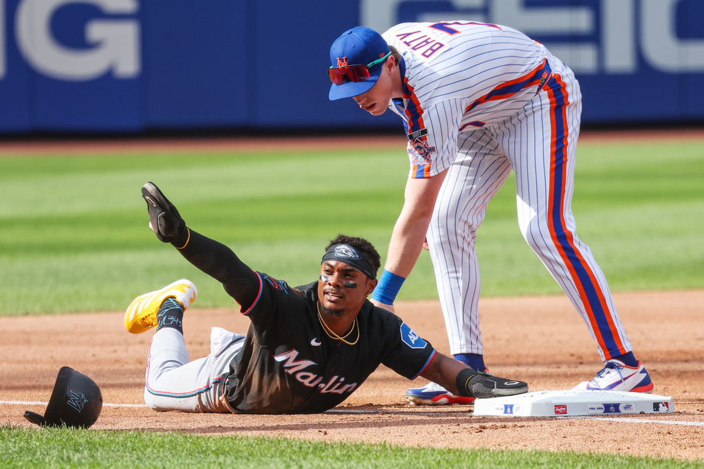 Miami Marlins' Esteury Ruiz , bottom, reacts after sliding to third base past New York Mets third baseman Brett Baty, top, during the second inning of a baseball game, Saturday, Aug. 1, 2026, in New York. (AP Photo/Heather Khalifa)