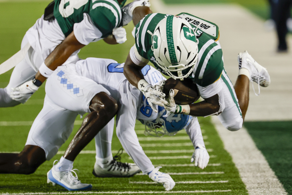 Charlotte running back CJ Stokes, right, dives for yardage against North Carolina defensive back Marcus Allen, bottom left, during the first half of an NCAA college football game in Charlotte, N.C., Saturday, Sept. 6, 2025. (AP Photo/Nell Redmond)