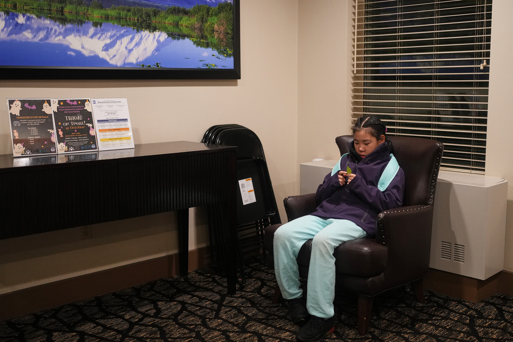 Rayann Martin, a 10-year-old from the village of Kipnuk who was displaced by ex-Typhoon Halong, holds a leaf while waiting in her hotel lobby for a bus to take her to her new school at College Gate Elementary, where students spend half their time learning in Yup'ik language immersion, Friday, Oct. 31, 2025, in Anchorage, Alaska. (AP Photo/Lindsey Wasson)