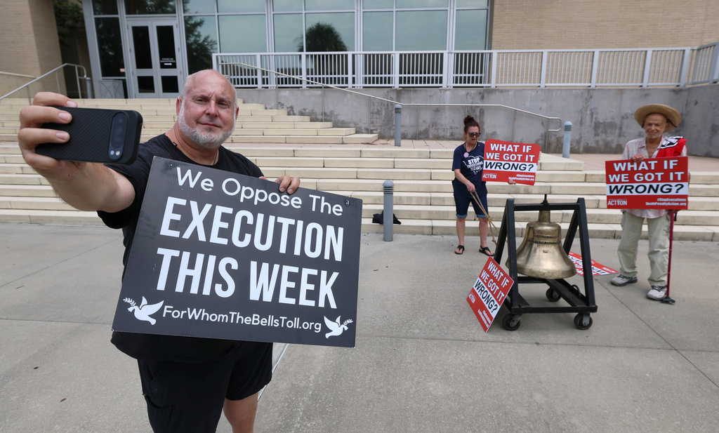 Death penalty protester Abe Bonowitz, foreground, casts a livestream as a bell is tolled during a demonstration in front of the Lake County Courthouse in Tavares, Fla., Tuesday, July 28, 2026. (Joe Burbank/Orlando Sentinel via AP)