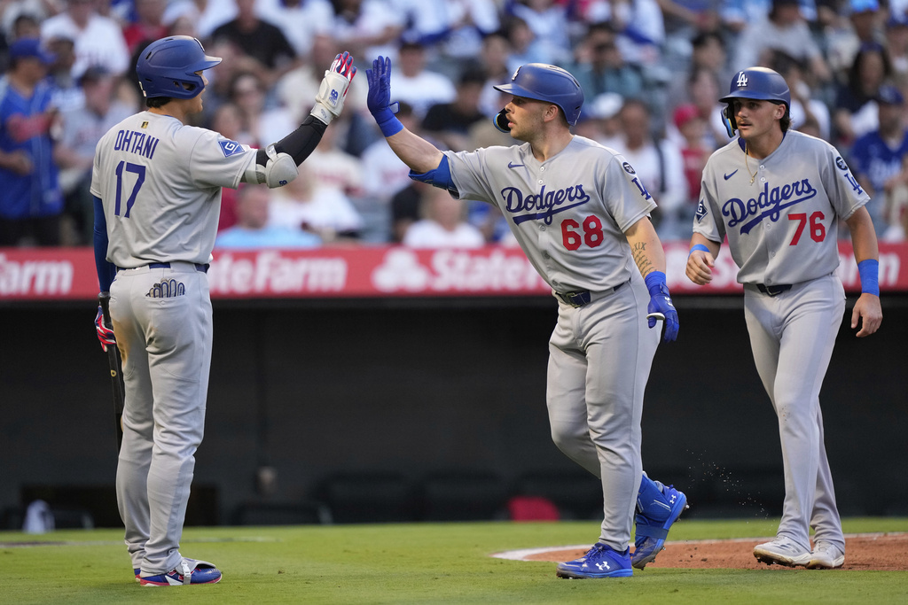 Los Angeles Dodgers' Dalton Rushing, center, is congratulated by Shohei Ohtani, left, after hitting a two-run home run as Alex Freeland walks behind during the second inning of a baseball game Tuesday, Aug. 12, 2025, in Anaheim, Calif. (AP Photo/Mark J. Terrill)