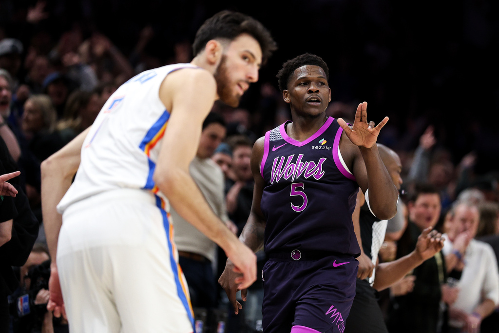Minnesota Timberwolves guard Anthony Edwards, right, celebrates his three-point basket as Oklahoma City Thunder center Chet Holmgren, left, looks on during the first half of an NBA basketball game, Friday, Dec. 19, 2025, in Minneapolis. (AP Photo/Matt Krohn)