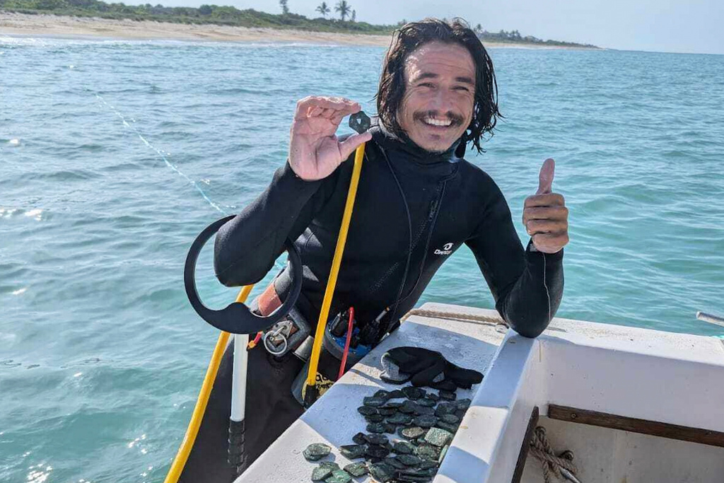 In this undated photo provided by shipwreck salvage company 1715 Fleet- Queens Jewels, LLC, diver Levin Shavers shows coins uncovered from a Spanish shipwreck off the Atlantic coast of Florida, 2025. (1715 Fleet - Queens Jewels, LLC via AP)