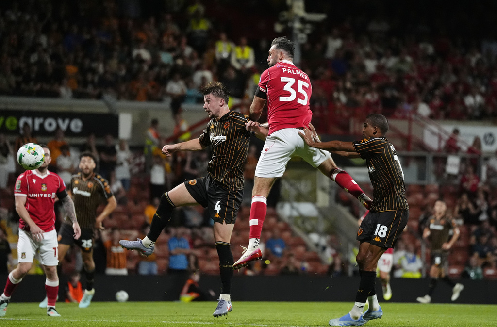 Wrexham's Ollie Palmer, top, scores during the English League Cup first round soccer match between Wrexham and Hull City at SToK Racecourse, Wrexham, Wales, Tuesday Aug. 12, 2025. (Nick Potts/PA via AP)